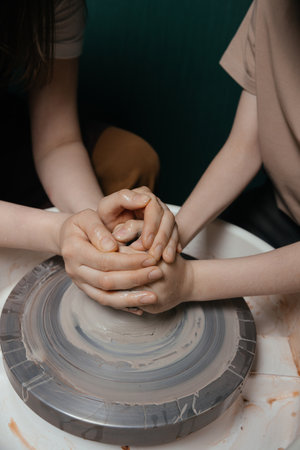 Potter shaping a ceramic artwork on a wheel. Hands in clay. Artistic pottery workshopの写真素材