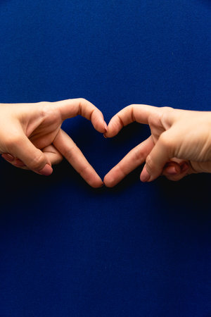 Female hands heart shape on blue background
