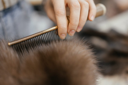 Female furrier grooming fur with iron comb in workshop