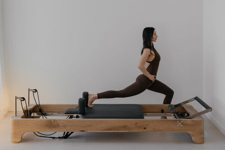 Woman practicing Pilates on wooden reformer machine