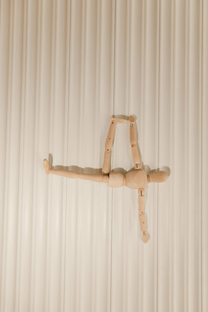 Close up of a small wooden mannequin performing various yoga and Pilates poses on a light...