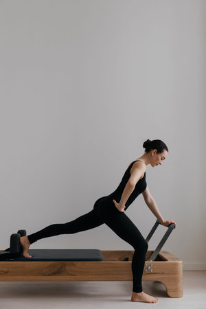 Pilates reformer training machine. Athletic woman practices pilates on professional reformer machine