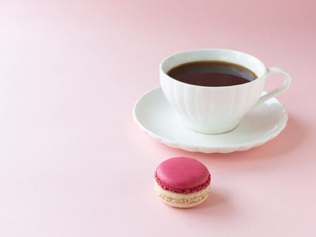 A white cup of coffee with delicious macaroon on the pink backgroundの写真素材