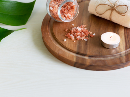 Beautiful pink Himalayan salt, candle and towel on wooden plank. Relaxation and spa concept.の写真素材