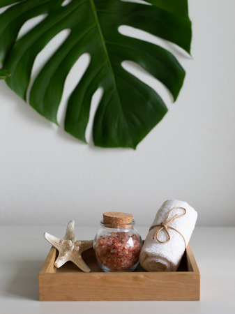Beautiful pink Himalayan salt, white towel and starfish in wooden box. Decorated with monstera leaf. Relaxation and spa concept.の写真素材
