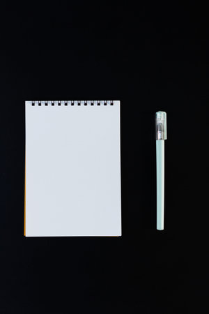 A note pad and pen on the black background. Flat-lay, top view.