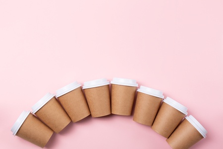 Many craft cardboard cups of coffee or tea to go on the pastel pink background. Take away coffee concept. Copy-space for your text.の写真素材