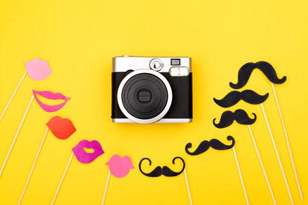 Photo booth props and instant camera on the yellow background. Wedding, party or Birthday background. Flatlay, top view.の写真素材