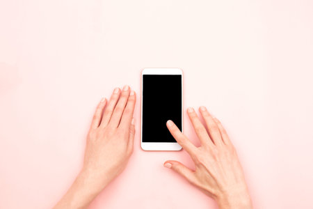 Woman's hands and a smartphone. One finger touchs a big screen. Mock up for your design. Copy space....