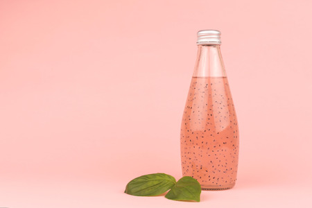 Bottle of basil seed drinks on pastel pink background. Healthy and refreshing beverage. Copy space for your text.の写真素材