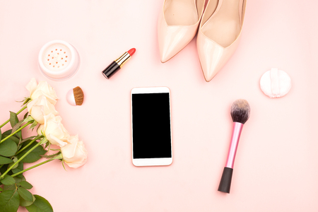 Perfect feminine background with a smartphone, cosmetics, shoes and flowers. The screen is mock up for your design. Blogging, freelance or online shopping concept. Flat-lay.の写真素材