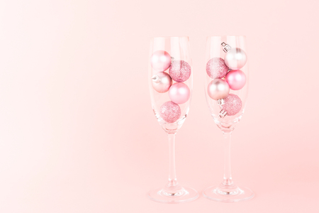 Two champagne glasses with pink Christmas tree decoration inside. Romantic celebration creative concept. Holiday and New Year toast vibes. Copy space for your text.の写真素材
