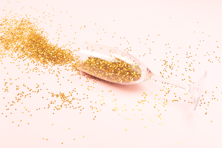 Champagne glass with star shaped confetti inside. Spilled drink. Romantic celebration creative concept. Holiday and New Year toast vibes. Copy space for your text.の写真素材