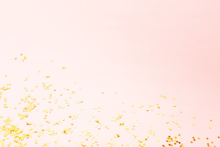 Golden star shaped confetti scattered on pastel pink background. Holiday and festive vibes. Christmas, New Year and Birthday concept. Cpy space for your text.の写真素材
