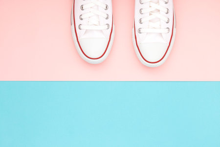 White sneakers on the pastel pink and blue background. Trendy colors. Copy-space for your text....