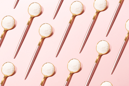 Pattern made with spoons with collagen or protein powder on pale pink background. Natural beauty and health supplement for skin, bones, joints and gut. Plant or fish based. Flatlay, top view.の写真素材