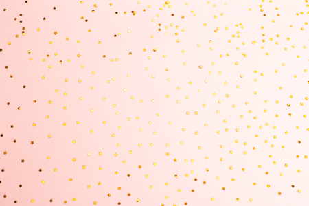 Golden star shaped confetti on pink background. Christmas, New Year, party concept. Flat-lay, top view. Copy space for text.の写真素材