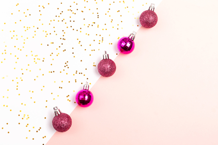 Christmas decor in plastic pink color on white and pink combination background. Decorated with star shaped gold confetti.  Holiday and New Year concept. Copy space for text.の写真素材