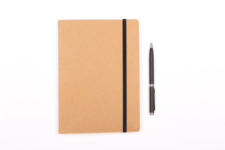 Closed notepad and a pen on white background. Stationery concept. Flat-lay, top view.の写真素材