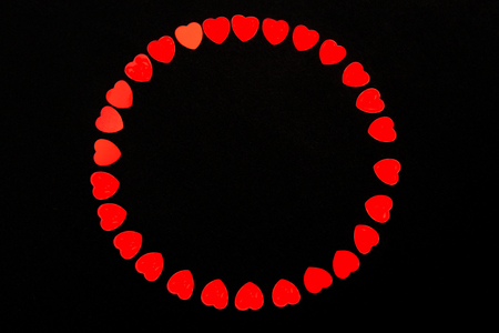 Valentine's day background made from heart shape confetti on black placed in wreath. Isolated on black.Bold red color. Love and passion concept. Flatlay, top view. Stylish and trendy image.の写真素材