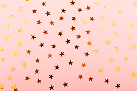 Gold star shape confetti on pink background. Festive vibes. Flat lay, top view.の写真素材