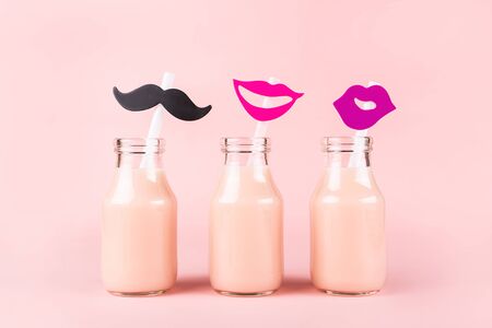 Three bottles of drink with funny straws on pink background. Pik yogurt, strawberry milk, smoothie or other beverage.の写真素材