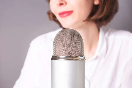 Unrecognizable girl and the microphone. Podcast, ASMR, livestream, video recording concept.の写真素材