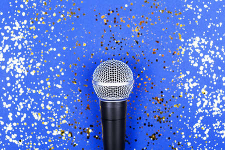 A microphone on blue background decorated with confetti. Minimal compostion.の写真素材