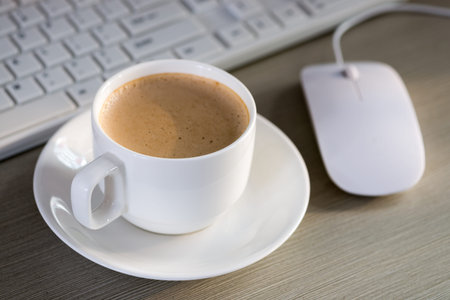 Close-up of the coffee, cellphone, pen and a cup of keyboard on the desktop