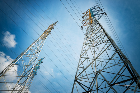 electricity transmission pylon silhouetted against blue sky at duskの写真素材