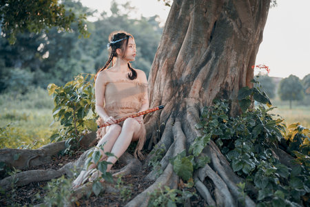 nostalgic theme, girl playing flute under treeの写真素材