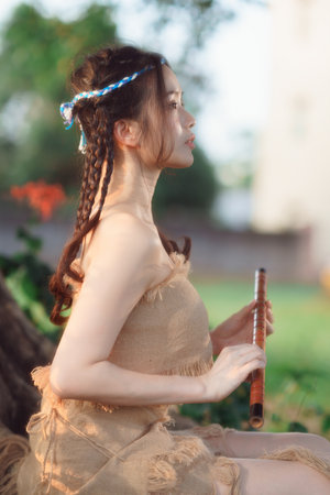 nostalgic theme, girl playing flute under treeの写真素材