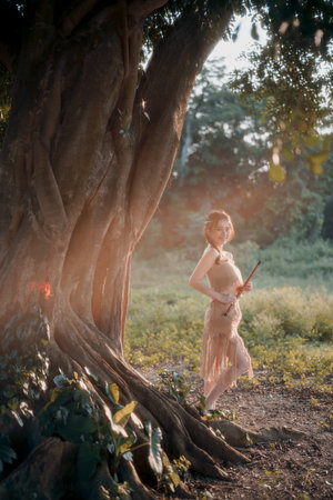 nostalgic theme, girl playing flute under treeの写真素材