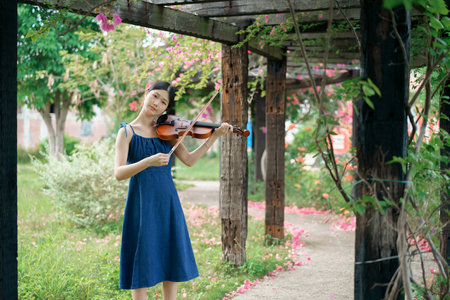 The girl is playing the violin in the gardenの写真素材