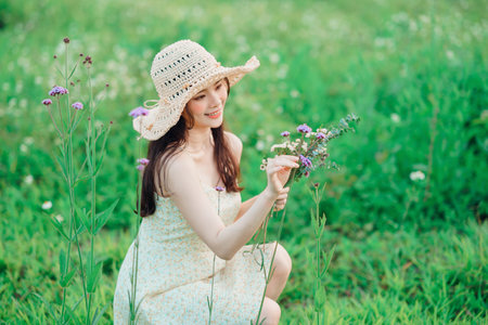 the fashion girl is holding the bouquet on the grassの写真素材