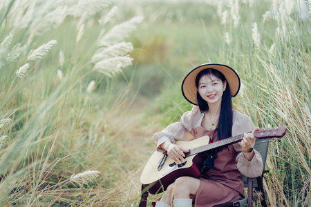 Woman playing a guitar at a campsiteの写真素材