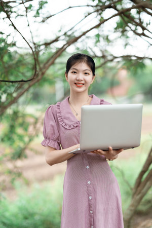 The pretty girl uses the laptop computer in the parkの写真素材