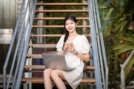 Female college students use laptops on campusの写真素材