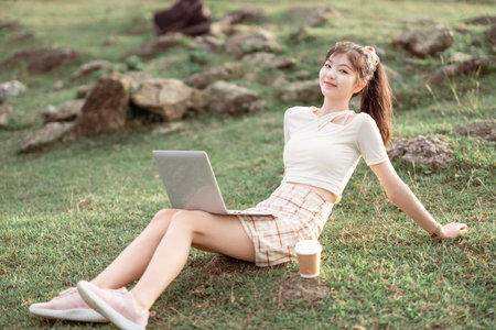 The girl uses a laptop computer on the lawnの写真素材