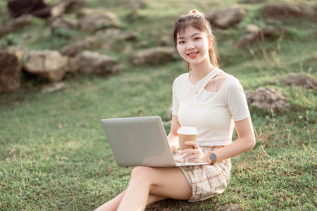 The girl uses a laptop computer on the lawnの写真素材