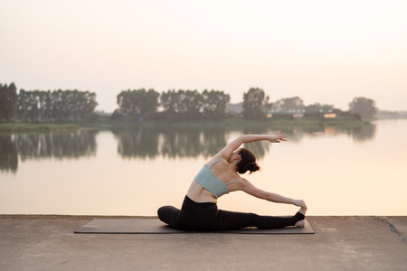 The girl is doing yoga by the lakeの写真素材