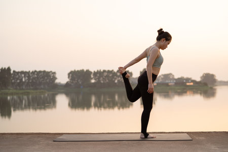 The girl is doing yoga by the lakeの写真素材