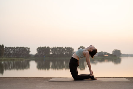 The girl is doing yoga by the lakeの写真素材