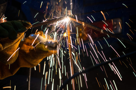 Young man with protective mask welding in a factory