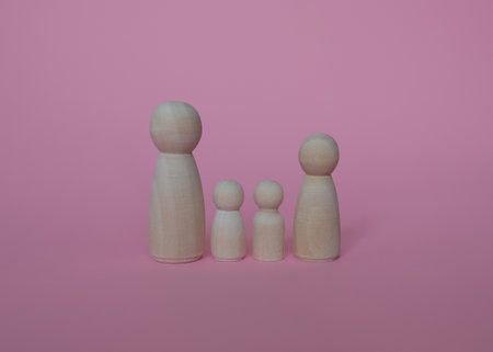 Wooden figures of people on a pink background. Teamwork conceptの写真素材