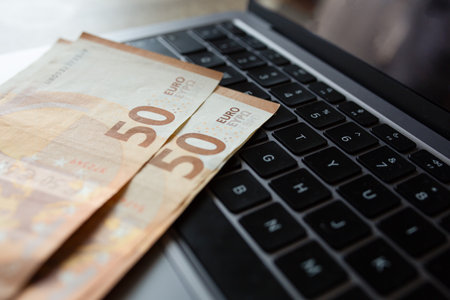 Euro banknotes on laptop keyboard. Concept of cash money, digital payments and financial transactionsの写真素材