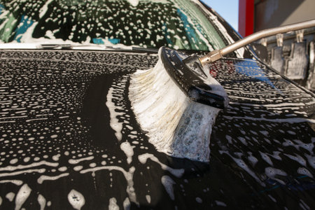 Washing black car with foam and brush, closeup of photoの写真素材
