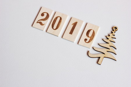 2019 numbers wooden symbol of the new year lying in a line on the white leather surface next to the wooden figure Christmas treesの写真素材