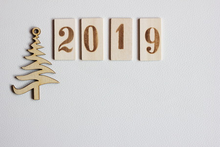 2019 numbers wooden symbol of the new year lying in a line on the white leather surface next to the wooden figure Christmas treesの写真素材