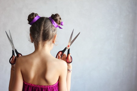 Hairstyle and haircare concept. Hairdressing services. Girl holding scissors. Hair with ribbons.の写真素材